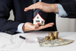 Inversionista cubriendo una casa de juguete sobre dinero para mostrar cómo eligen propiedades los inversionistas inteligentes.